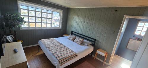 a bedroom with a bed and two windows at Casa completa para 6 personas centro Puerto Montt, 700 metros estatua enamorados in Puerto Montt