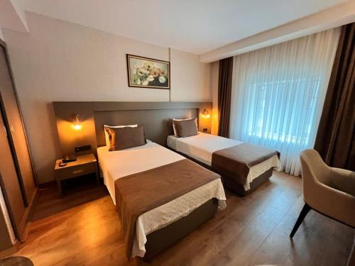 a hotel room with two beds and a chair at Adana Time Business Hotel in Adana