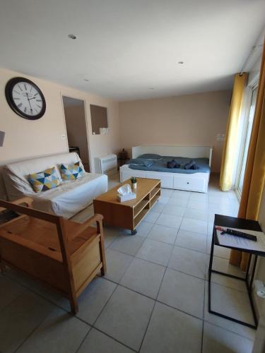 a living room with two beds and a clock on the wall at Studio La Gière in Beaumes-de-Venise
