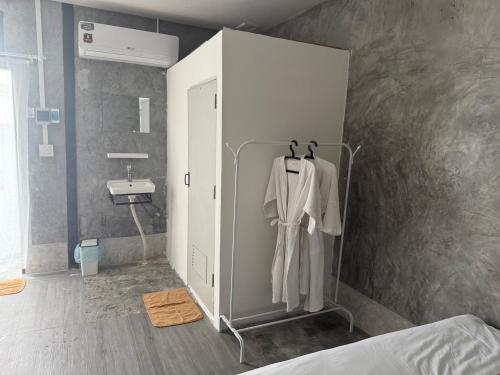a bathroom with a sink and a robe on a rack at Bird Nest Hostel in Ko Tao