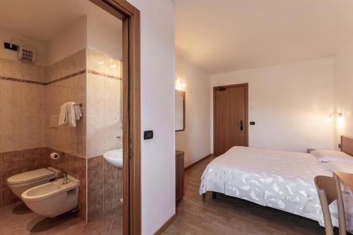 a bathroom with a bed and a sink and a toilet at Hotel Posta in Comano Terme