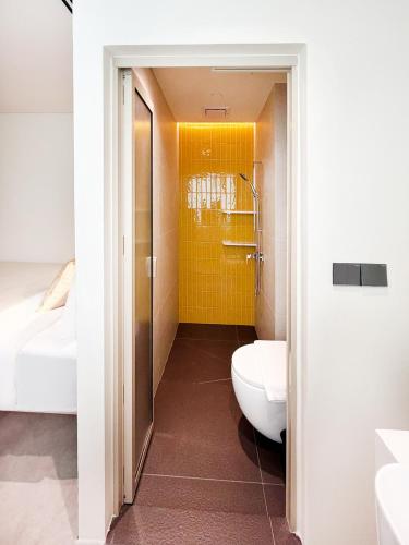 a bathroom with a toilet and a yellow wall at Coliwoo Midtown - CoLiving in Singapore