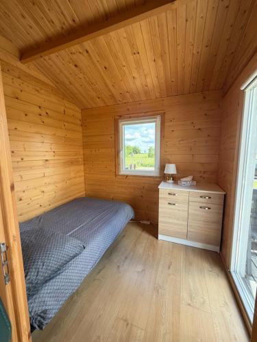 a bedroom in a wooden cabin with a bed and a window at Domki Me Mazury in Giżycko
