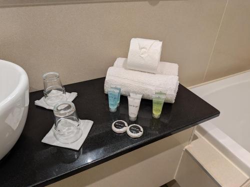 a bathroom with a black counter with towels and glasses at Queens Hotel Belfast in Belfast