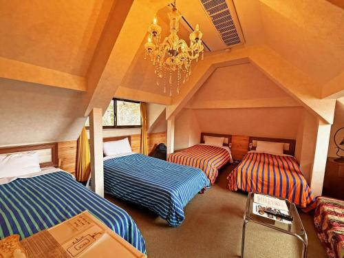 a room with three beds and a chandelier at Nikko Park Lodge Mountain Side in Nikko