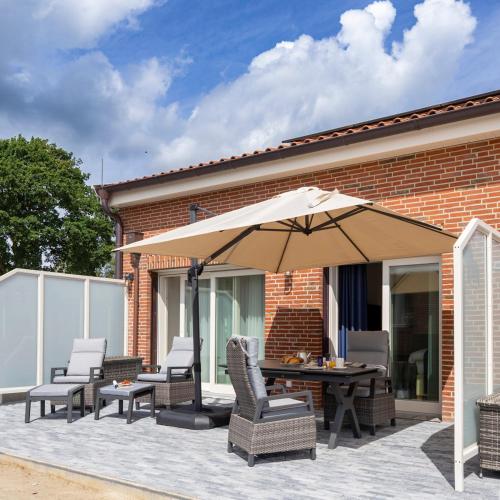 a patio with a table and chairs and an umbrella at Gulfhof bei Kletzsch Apartments & Ferienwohnungen in Großefehn Ostfriesland in Großefehn 