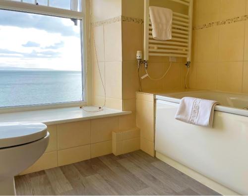 ein Badezimmer mit Badewanne, Toilette und Fenster in der Unterkunft Caerwylan Hotel in Criccieth