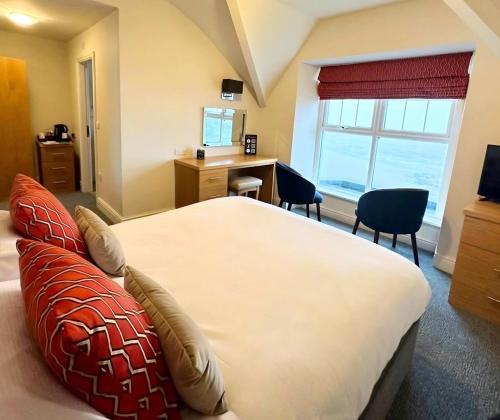 ein Schlafzimmer mit Bett, Schreibtisch und Fenster in der Unterkunft Caerwylan Hotel in Criccieth