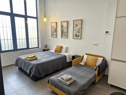 a bedroom with two beds and a couch and windows at Jardín Viveros-Turia in Valencia