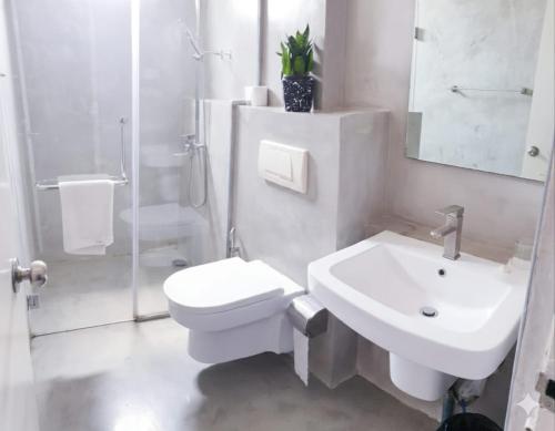 a white bathroom with a toilet and a sink at MountBaylk in Mount Lavinia