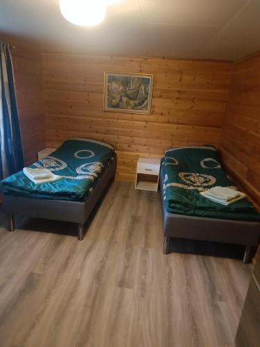 two beds in a room with wooden walls at Aurora appartmens in Senja
