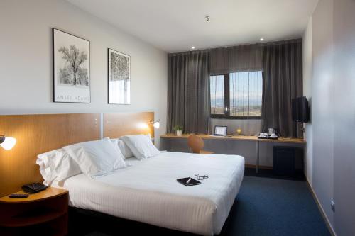 a hotel room with a large bed and a desk at Hotel Porta de Gallecs in Mollet del Vallès