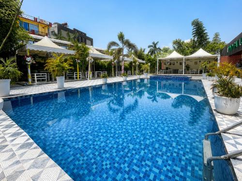 a large swimming pool with blue water in a resort at Landmark, Rewa - AM Hotel Kollection in Rewa