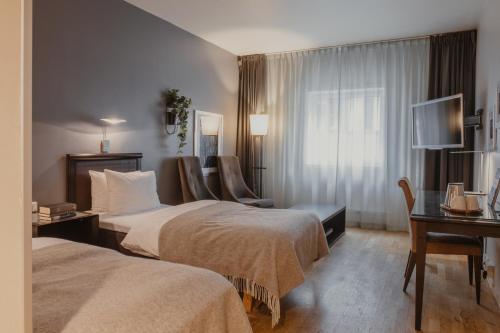 a hotel room with two beds and a desk at Home Hotel Aurora in Tromsø