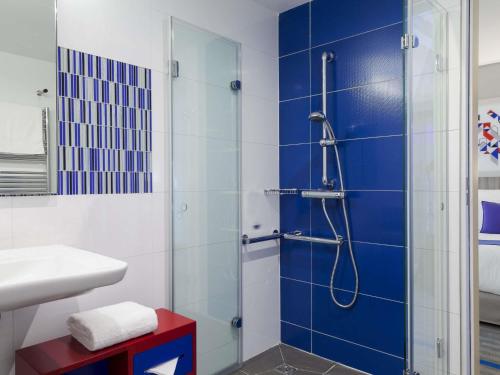 a bathroom with a shower with a blue wall at Mercure Toulouse Sud in Toulouse