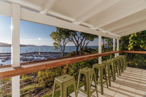 a row of stools on a balcony with a view of the ocean at Casa Airlie in Airlie Beach
