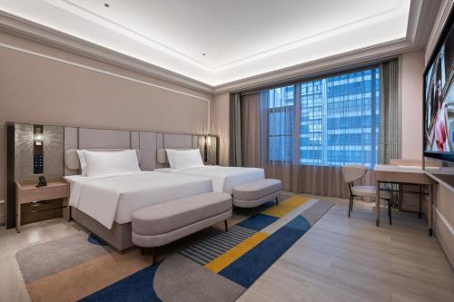 a hotel room with a bed and a tv at Mercure Kunming Wujiaba in Kunming