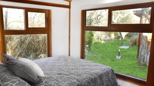 a bedroom with a bed and two windows with a view at Cabañas Boutique Pipi Cucu in Colón