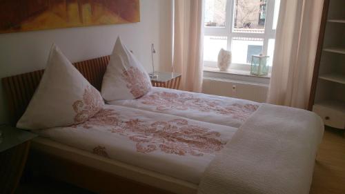 Bett mit weißer Bettwäsche und Kissen mit Fenster in der Unterkunft Patio 1 in Bremen
