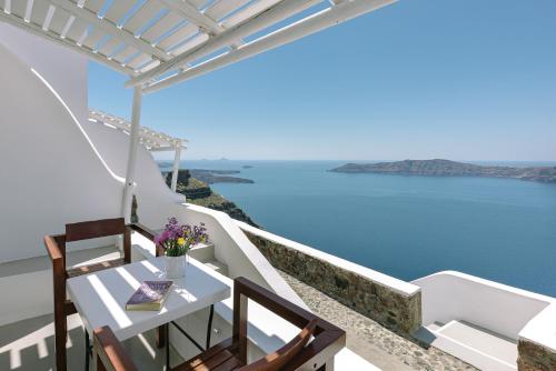 a white table and chairs with a view of the ocean at Afroessa Hotel by Caldera Houses in Imerovigli