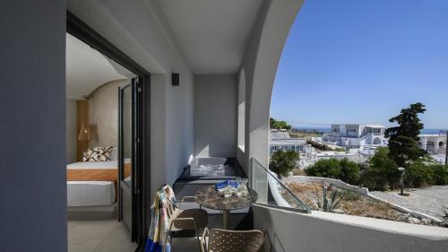a room with a balcony with a bed and a table at Anemone Luxury Suites in Fira