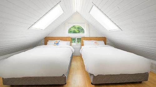 two beds in a attic room with skylights at Gapyeong Dangdangi Pet Pension Green in Gapyeong