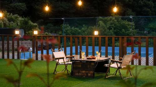 a table and chairs in a yard with a pool at Gapyeong Dangdangi Pet Pension Green in Gapyeong