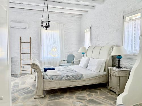 a white bedroom with a bed and a chair at Koundouros 186 View in Koundouros