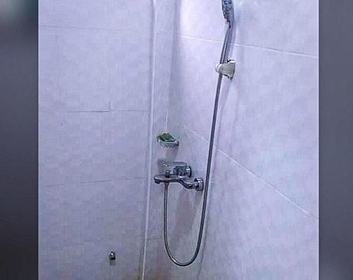 a shower in a white tiled bathroom at Wisny Guest House in Kasoa
