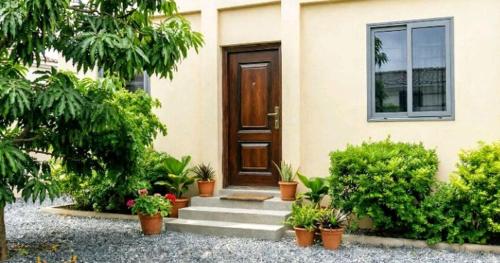 a house with a wooden door and some plants at Wisny Guest House in Kasoa