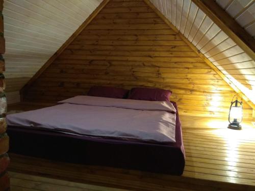 a bed in a wooden attic with a light at Хатуля in Oleshnya