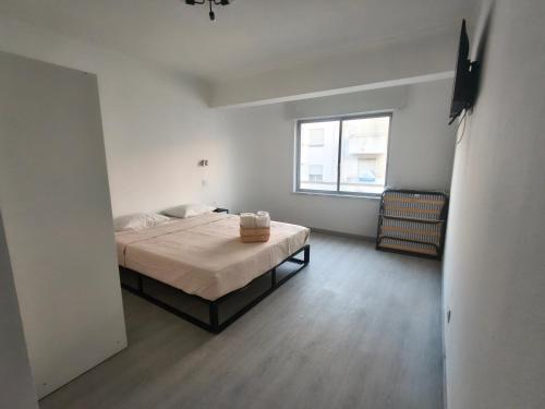 a white room with a bed and a window at Cubo Rooms Olhão in Olhão