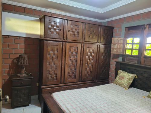 a bedroom with a bed and wooden cabinets and a window at Flat Alto Padrão in Gravatá