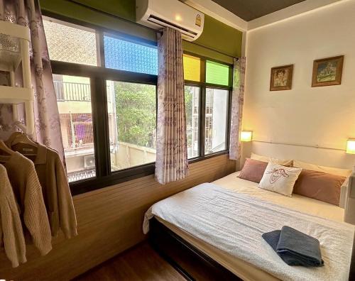 a bedroom with a bed and a large window at Bangkok Sanookdee Hostel in Bangkok