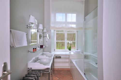 a bathroom with two sinks and a tub and a window at Schlossgut Gross Schwansee in Groß Schwansee