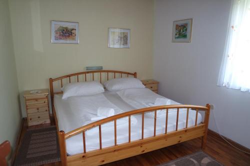 a bedroom with a wooden bed with white sheets at Haus Pock Apartments in Lake Pressegg