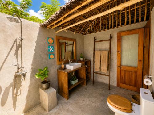 ein Badezimmer mit Toilette, Waschbecken und Spiegel in der Unterkunft Beach Bohème in Paje