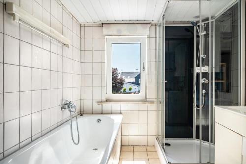 a white bathroom with a tub and a window at Haus Mersche in Gösenroth