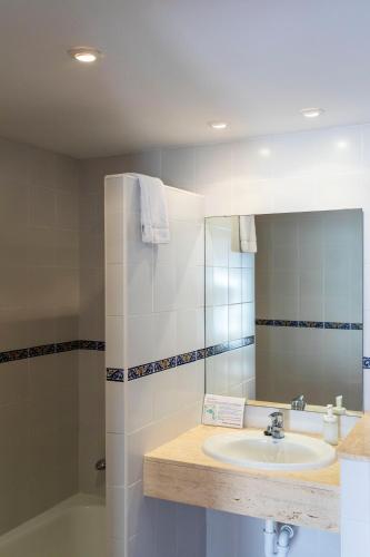 a bathroom with a sink and a mirror and a tub at Hostal Cala Ratjada in Cala Ratjada