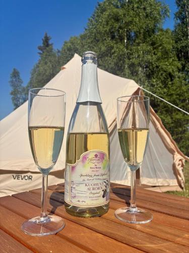 a bottle of wine and two glasses on a table at Glamping Arctic Ukuli in Rovaniemi