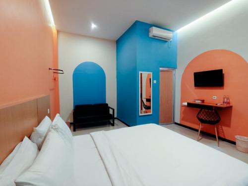 a hotel room with a bed and a desk at Tripletree Kenaro Hotel in Blimbing