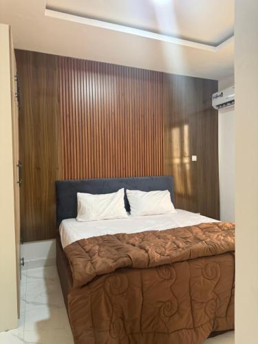 a bedroom with a large bed with a wooden wall at Pristine Residences Premium 2 Bedroom Apartment Ajah Lagos in Lekki