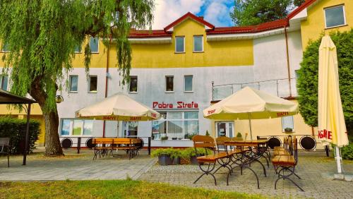 a patio with tables and umbrellas in front of a building at Hotelik MOSiR Reda in Reda