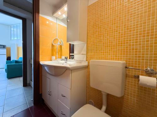 a bathroom with a sink and a toilet and yellow tiles at DIMORA Concept - Yellow Apartment in Ceriale