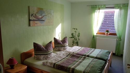 Un dormitorio con una cama con almohadas moradas y una ventana en Ferienwohnung Giesa, en Jena