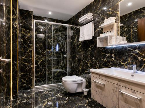 a bathroom with a toilet and a shower and a sink at Golden River Hotel By Continent in Arnavutköy