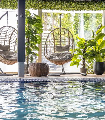 a swimming pool with two rattan chairs and plants at Säröhus Hotel, Conference & Spa in Särö