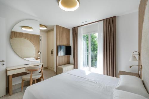 a hotel room with a bed and a desk and a mirror at Appartement Rosalia Delta Resort 741 in Ascona
