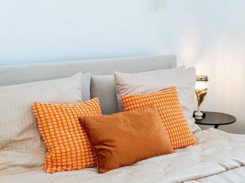 a white bed with orange and white pillows on it at Ahrensböker Residenz 7 in Stockelsdorf