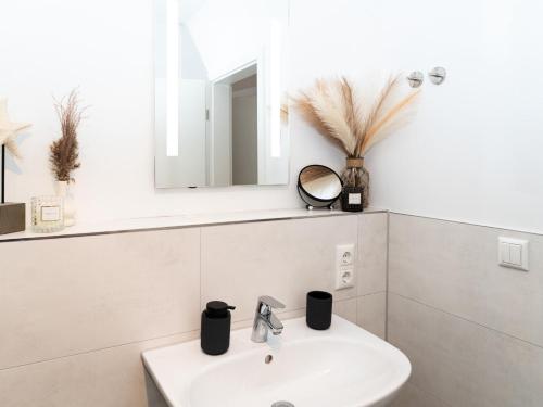 a white bathroom with a sink and a mirror at Ahrensböker Residenz 7 in Stockelsdorf